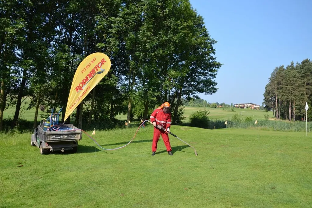 Ošetřování golfového hřiště Rodenatorem, vedle vlajka Rodenator a golfový vozík